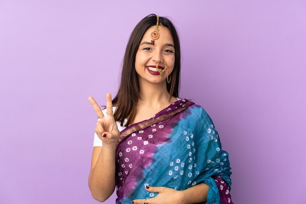 Jeune femme indienne isolée souriant et montrant le signe de la victoire