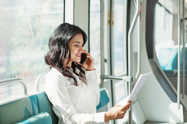 Jeune femme indienne lire des documents et parler au téléphone dans le tram de Dubaï