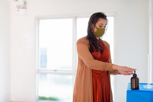 Jeune Femme Indienne Avec Masque à L'aide D'un Désinfectant Pour Les Mains Comme Bonne étiquette D'hygiène à L'intérieur
