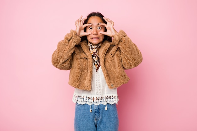 Jeune femme indienne métisse portant un court manteau en peau de mouton les yeux ouverts pour trouver une opportunité de succès.