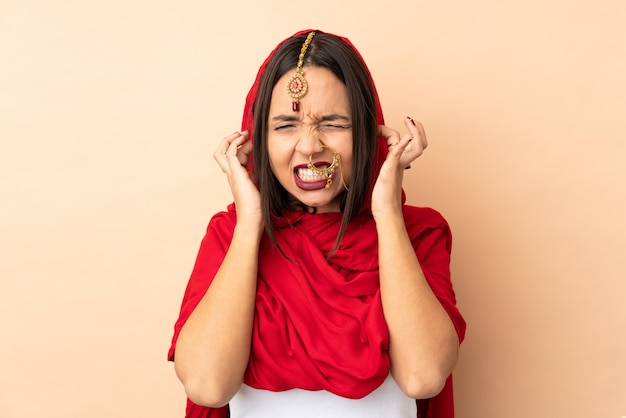 Jeune femme indienne sur mur beige frustré et couvrant les oreilles