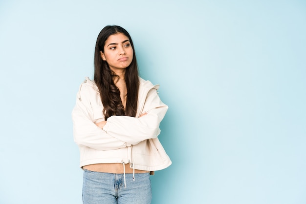 Jeune femme indienne sur mur bleu fatigué d'une tâche répétitive.