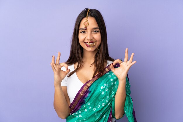 Jeune femme indienne sur mur violet montrant signe ok avec deux mains