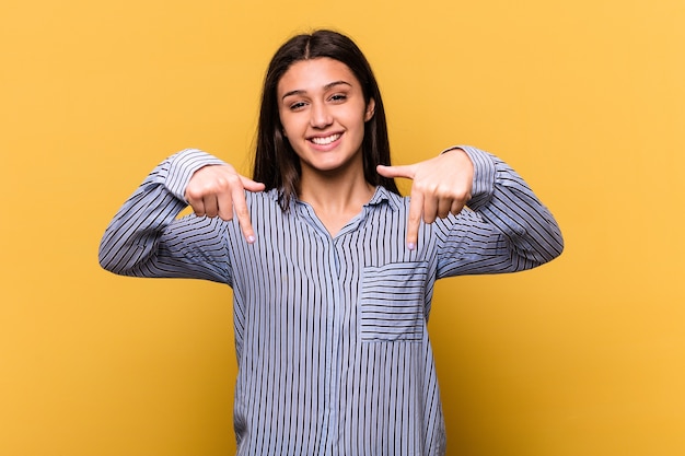 Jeune femme indienne sur les points jaunes vers le bas avec les doigts, sentiment positif.