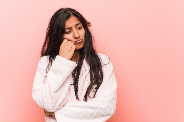 Jeune femme indienne portant un pyjama qui se sent triste et pensif, regardant l'espace vide.