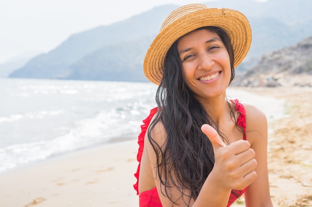 Jeune femme indienne pouce vers le haut sur la plage