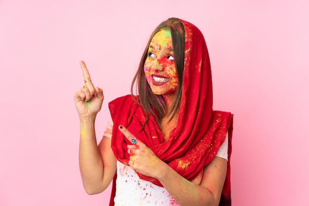 Jeune femme indienne avec des poudres de holi colorées sur son visage isolé sur mur rose