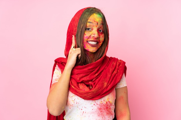 Jeune femme indienne avec des poudres de holi colorées sur son visage sur le mur rose en riant