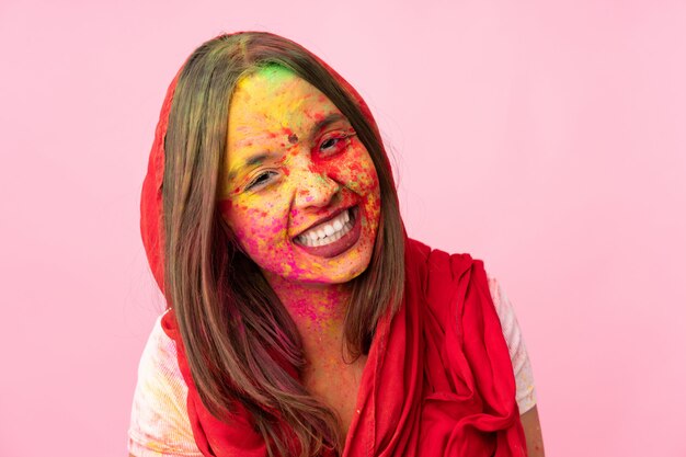 Jeune femme indienne avec des poudres de holi colorées sur son visage sur le mur rose