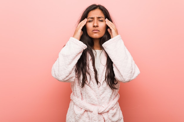 Jeune femme indienne en pyjama touchant les tempes et ayant mal à la tête.