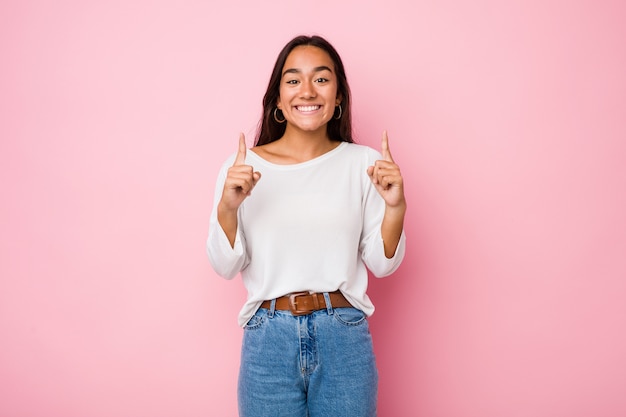 Jeune Femme Indienne De Race Mixte Indique Avec Les Deux Doigts Avant Montrant Un Espace Vide.