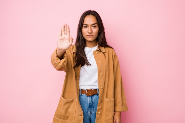 Jeune femme indienne de race mixte isolé debout avec la main tendue montrant le panneau d'arrêt, vous empêchant.