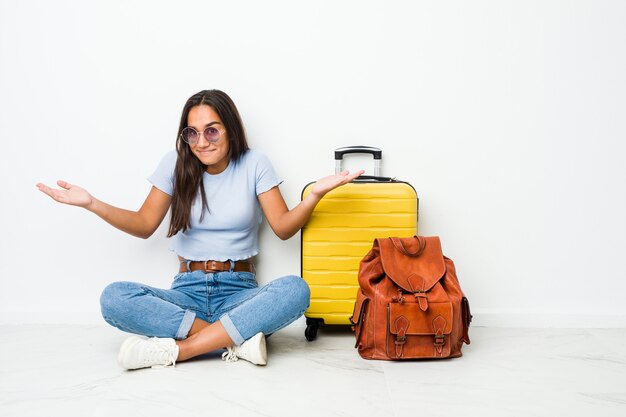 Jeune femme indienne de race mixte prête à partir en voyage doutant et haussant les épaules en remettant en question le geste.