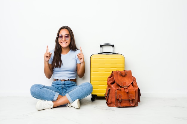 Jeune femme indienne de race mixte prête à partir en voyage indique avec les deux doigts avant montrant un espace vide.