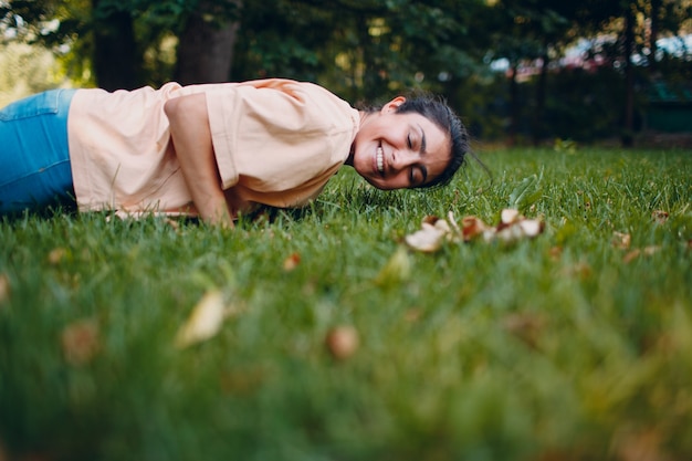 Une jeune femme indienne de remise en forme adulte fait des pompes et un bar sur l'herbe dans le parc d'été