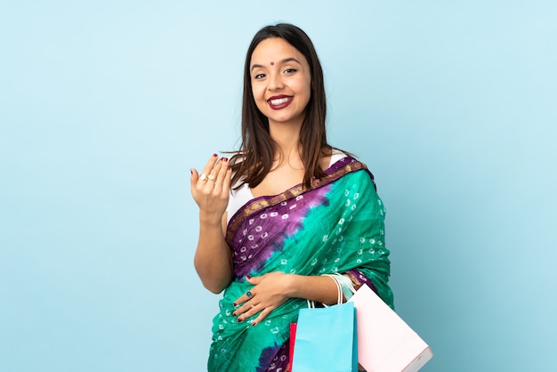 Jeune femme indienne avec des sacs à provisions invitant à venir avec la main
