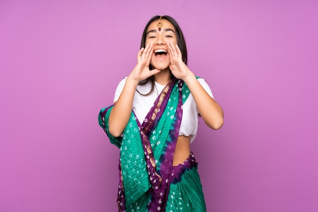 Jeune femme indienne avec sari isolé criant et annonçant quelque chose