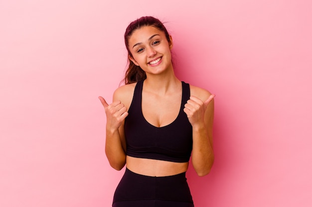 Jeune femme indienne de sport isolée sur un mur rose, levant les deux pouces vers le haut, souriant et confiant.