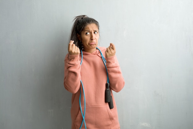 Jeune femme indienne sportive contre un mur triste et déprimé, faisant un geste de nécessité.