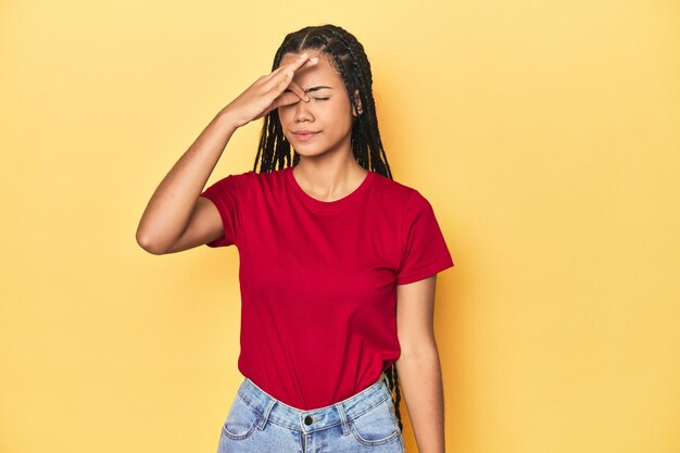 Jeune femme indonésienne sur fond de studio jaune ayant un mal de tête touchant le devant du visage