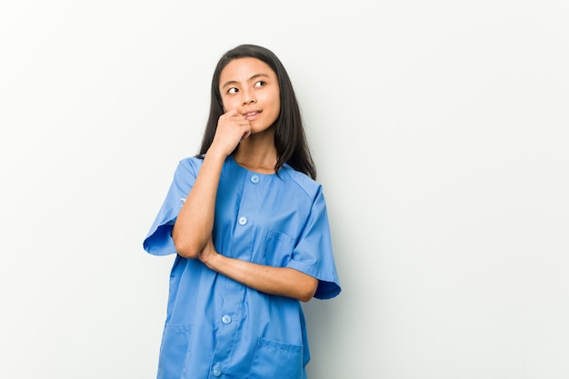 Jeune femme infirmière asiatique détendue penser à quelque chose en regardant un espace vide.