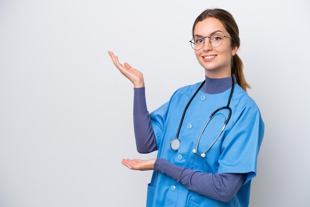 Jeune femme infirmière caucasienne isolée sur fond blanc tendant les mains sur le côté pour inviter à venir