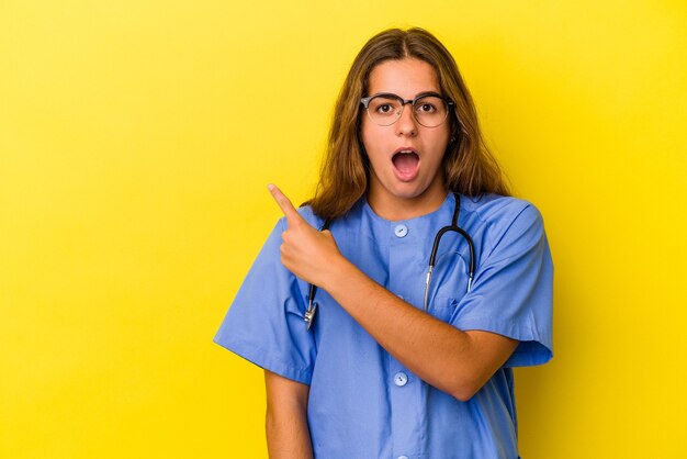 Jeune femme infirmière isolée sur fond jaune pointant vers le côté