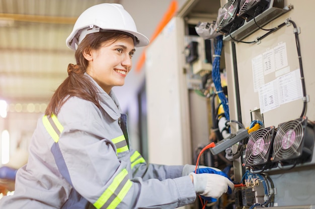 Jeune femme ingénieur sourire heureux test de maintenance tension du câble d'alimentation avec service haute tension grande alimentation de l'armoire