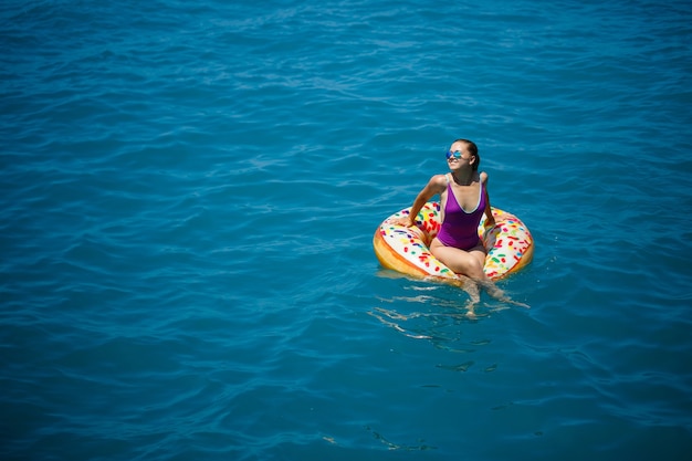 Jeune femme insouciante profitant d'une journée de détente en mer, flottant sur un anneau gonflable. Concept de vacances en mer. Mise au point sélective