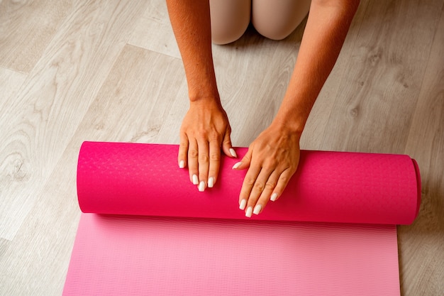 Jeune femme avec un instructeur de fitness aux cheveux longs en vêtements de sport beige se préparant à l'étirement et