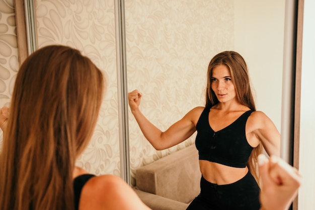 Jeune femme avec un instructeur de fitness aux cheveux longs en vêtements de sport noirs faisant des étirements et des pilates sur