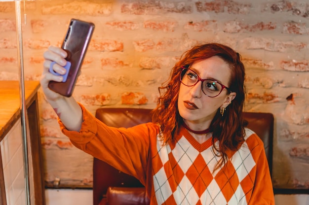 Jeune femme à l'intérieur d'un restaurant prenant un selfie avec son téléphone