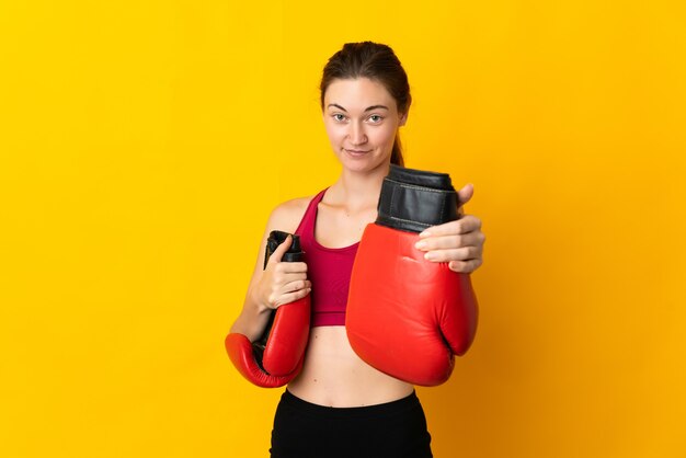 Jeune femme d'Irlande isolée sur fond jaune avec des gants de boxe