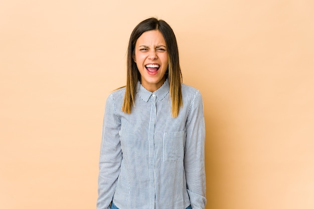 Jeune femme isolée sur fond beige criant très en colère, concept de rage, frustré.