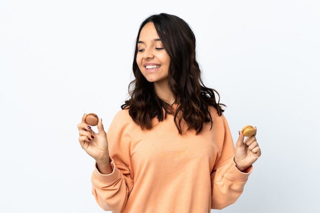 Jeune femme isolée sur fond blanc tenant des macarons français colorés et pensant