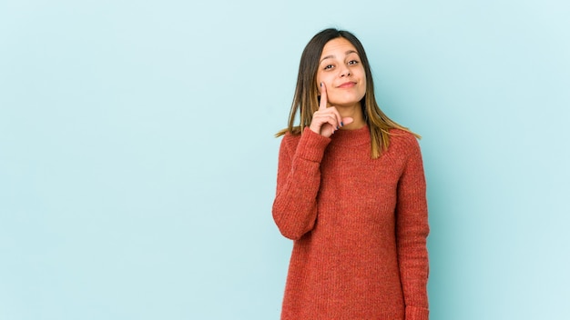 Jeune femme isolée sur fond bleu montrant le numéro un avec le doigt.