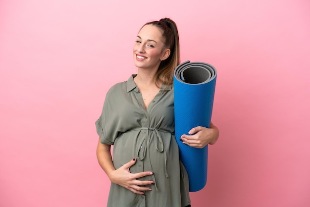 Jeune femme isolée sur fond rose enceinte et allant aux cours de yoga