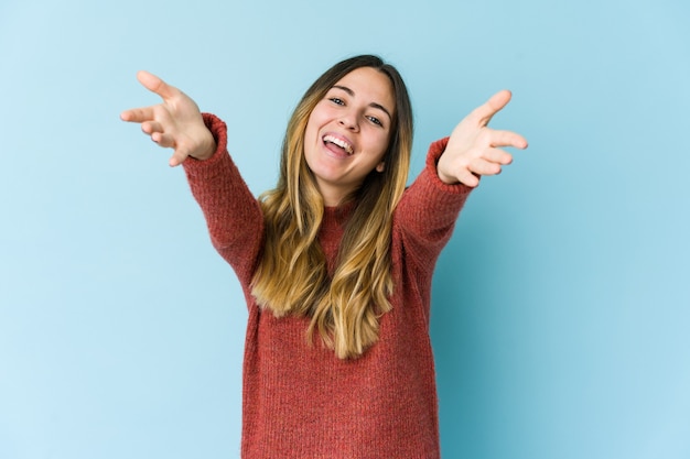 Jeune femme isolée sur un mur bleu se sent confiant en donnant un câlin à l'avant