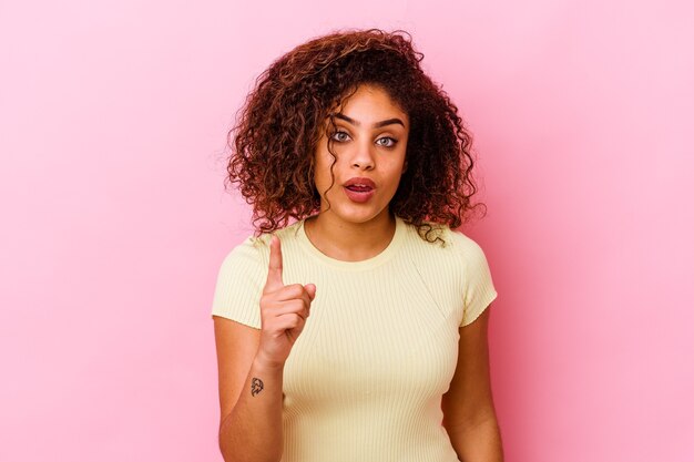 Jeune femme isolée sur un mur rose ayant une idée, concept d'inspiration