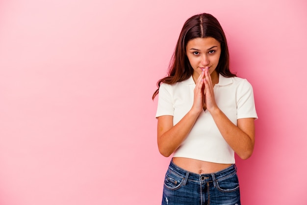 Jeune femme isolée sur un mur rose faisant plan à l'esprit, la mise en place d'une idée