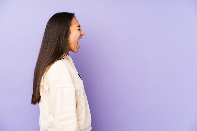 Jeune femme isolée sur un mur violet criant vers un espace de copie