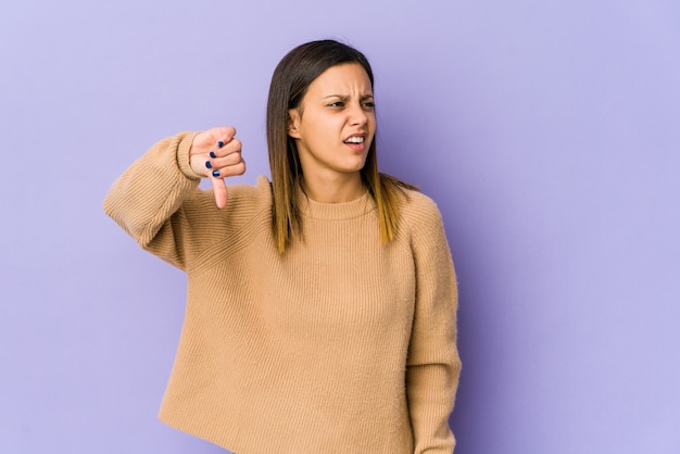 Jeune femme isolée sur un mur violet montrant le pouce vers le bas et exprimant l'aversion.