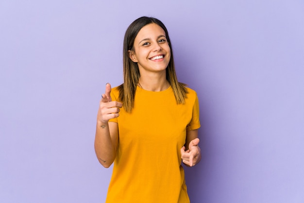 Jeune femme isolée sur un mur violet pointant vers l'avant avec les doigts.