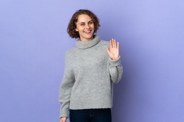 Jeune femme isolée saluant avec la main avec une expression heureuse