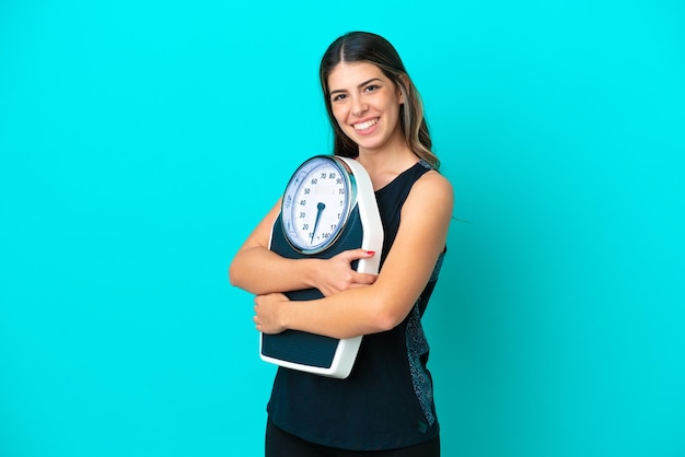 Jeune femme italienne isolée sur fond bleu avec balance