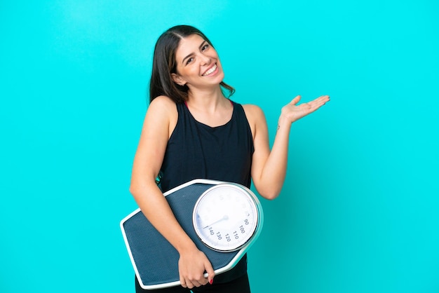 Jeune femme italienne isolée sur fond bleu avec balance