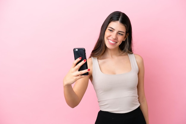 Jeune femme italienne isolée sur fond rose faisant un selfie