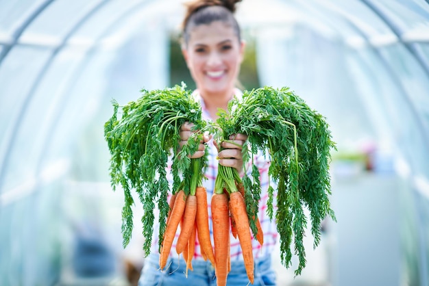 Jeune femme jardinier avec des carottes en serre
