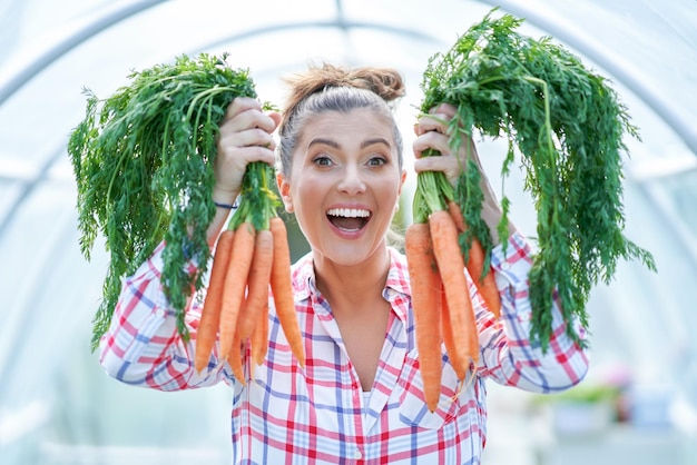 Jeune femme jardinier avec des carottes en serre