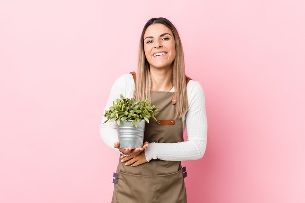 Jeune femme jardinier tenant une plante en riant et en s'amusant.